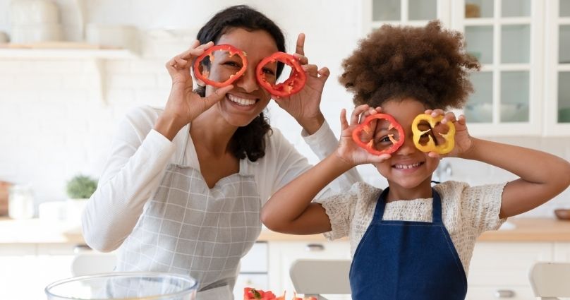 mom and daughter playing with bell peppers on their eyes