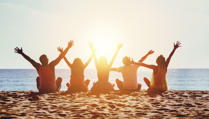 friends on the beach with their arms in the air | UV safety awareness