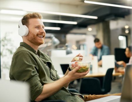 man happy at work eating lunch w headphones on 