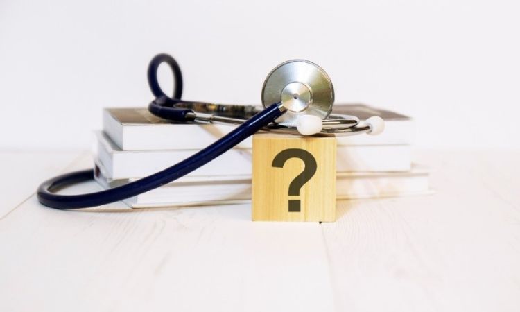 stethoscope on topp of a few books a block with a question mark on it