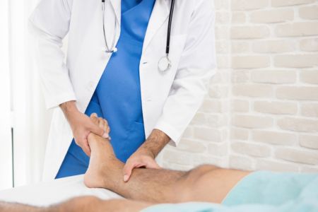 doctor with hands on examining a male patients leg
