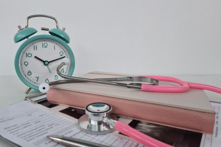 alarm clock near charts and a stethoscope 