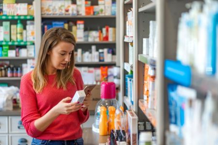 young woman reading an over the counter product in a pharmacy