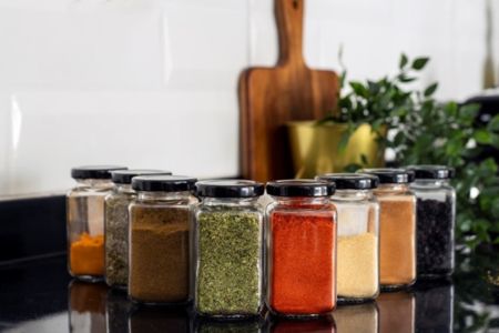 radom spices in individual glass jars without labels on a countertop