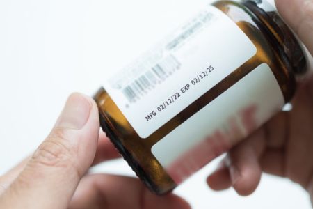 pill bottle in hand with an expired date on it