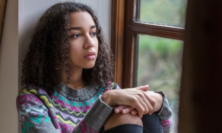 A young girl looking out a window in deep thought