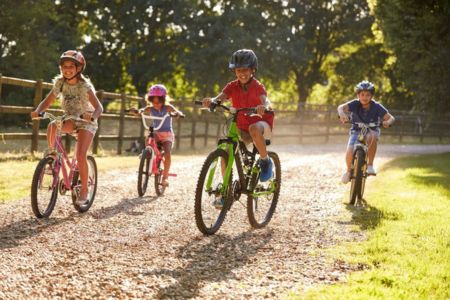 Kids riding bikes with helmets, practicing Summer safety for kids.