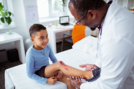Doctor treating a scrape on a kids knee 