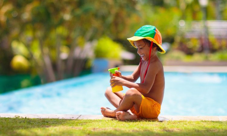 A young boy is playing with a toy on the grass near a pool.