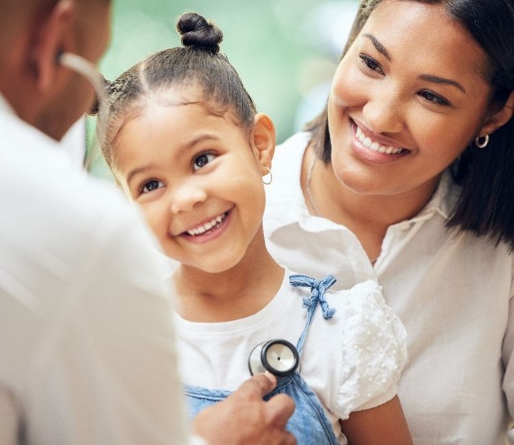 Mother and young daughter during a physical exam with a doctor using a stethoscope