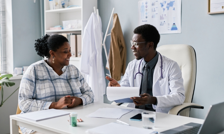 African American woman sitting with a male African American doctor in his office
