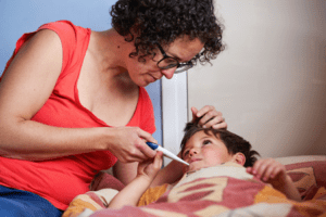 woman taking temperature of sick child