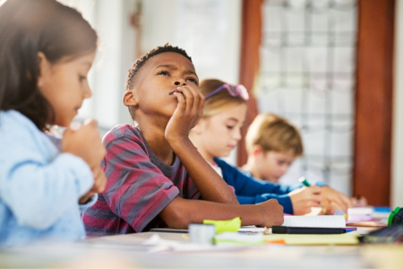 a child sitting and staring off into the distance with other classmates