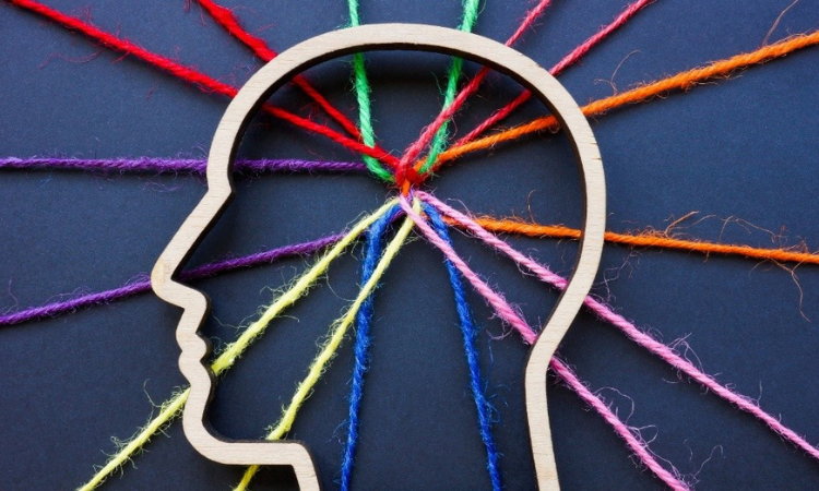 stencil of a human head with different color yarn all coming in to the center of his head from different directions