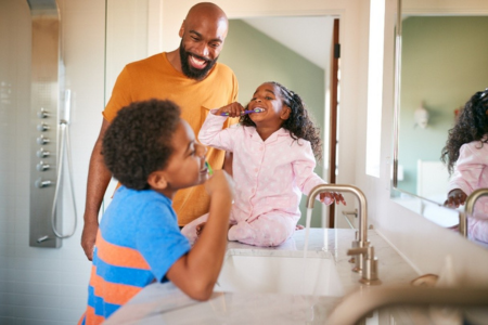 black male father with son and daughter brushing their teeth and having fun