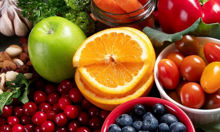 healthy laid out on a table with an orange, a green apple, tomatoes, almonds, cherry tomatoes