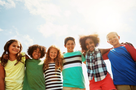 Young children standing side by side smiling outdoors 